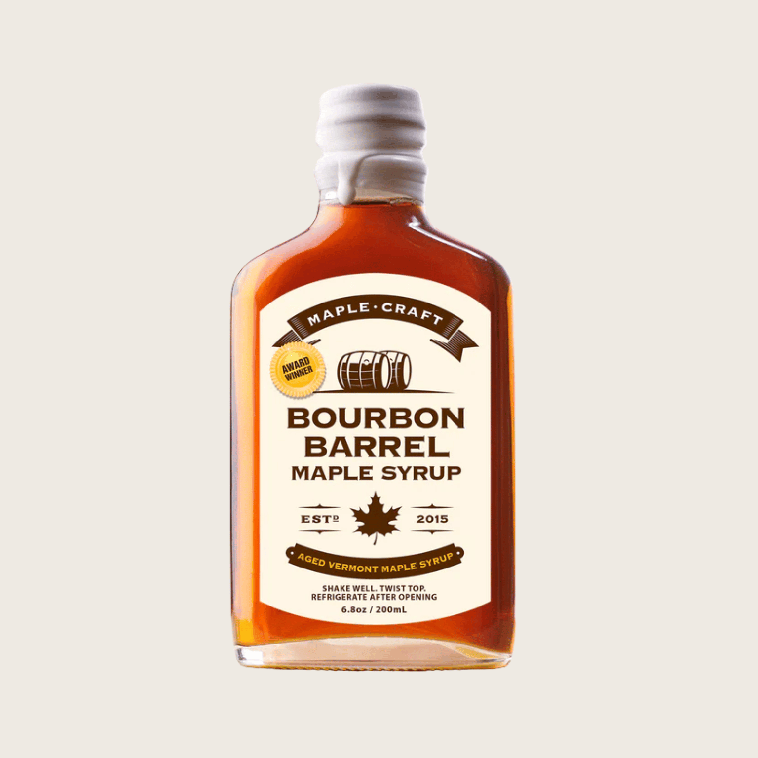 Bottle of Bourbon Barrel Maple Syrup with a white label on a beige background