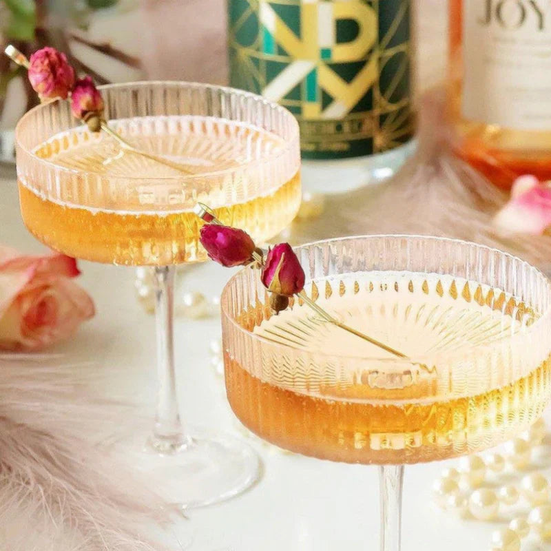 two cocktail glasses with floral garnishes and a bottle of monday non alcoholic gin in the background